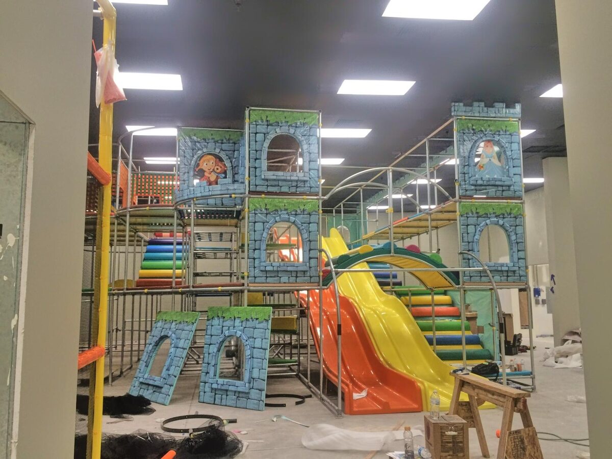 A castle-themed play structure with slides partway through installation